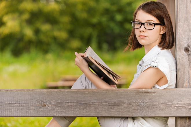 Girl reading a book outdoors.