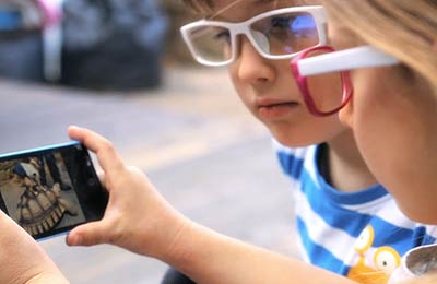 Children on a smartphone wearing Lutina protective glasses